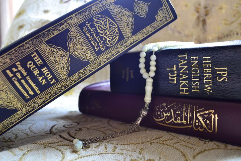 Photo of a copy of the Quran in Arabic, one in English, and the Jewish Tanakh in both Hebrew and English