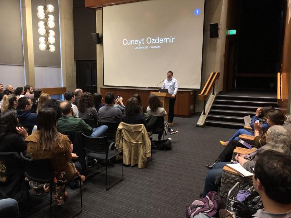 Cüneyt Ozdemir standing before a large crowd introducing his presentation.